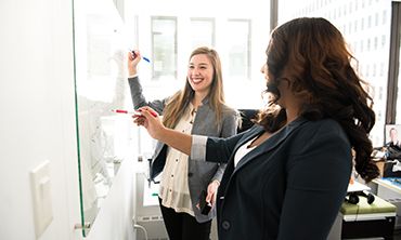 two women working at a whiteboard
